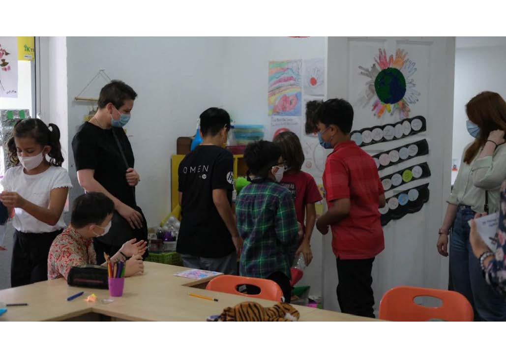 A group of students wearing masks and Dr Francesca Peruzzo and PhD researcher Bethan Morris-Tran are looking at a table where students’ school artefacts are displayed.