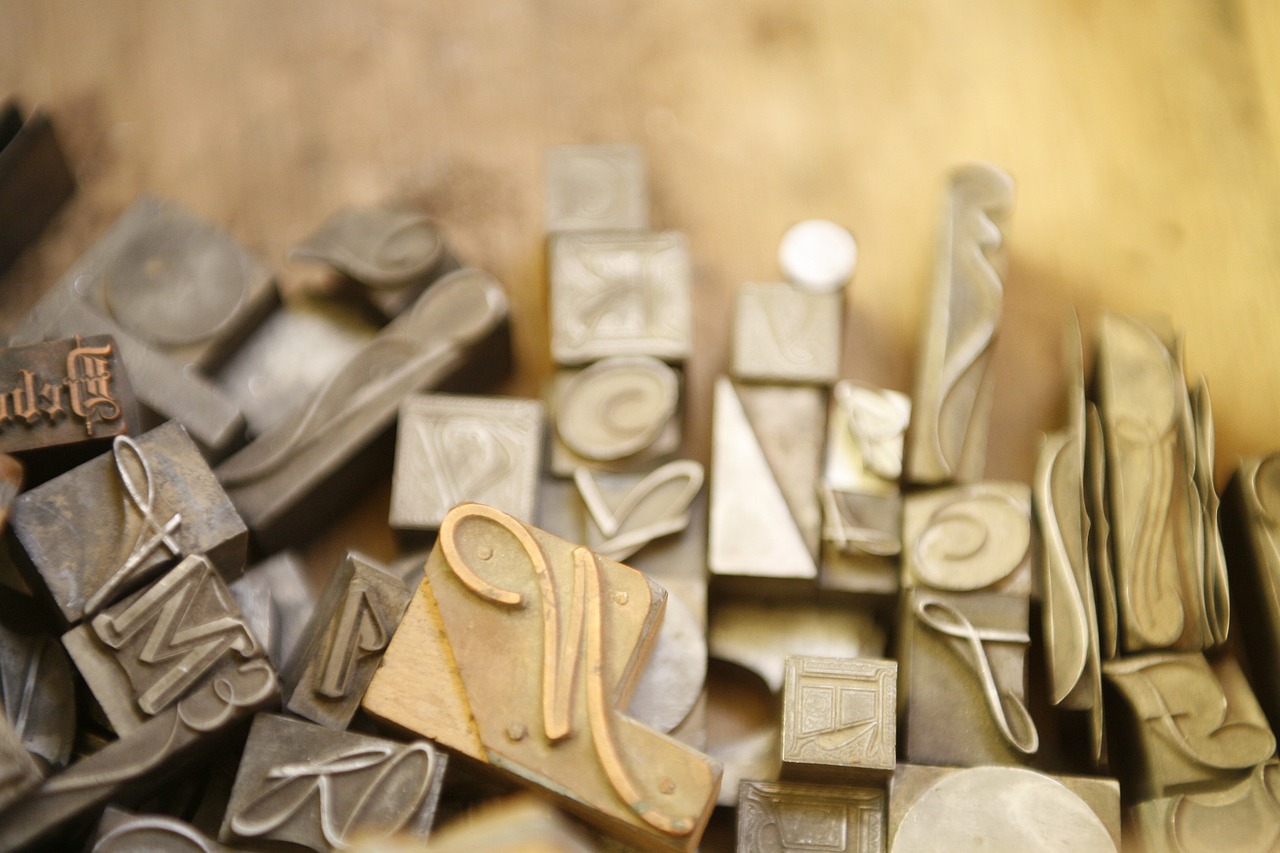 A collection of individual type forms – small metal stamps of individual letters in different fonts and sizes that would be used in an old-fashioned printing press.