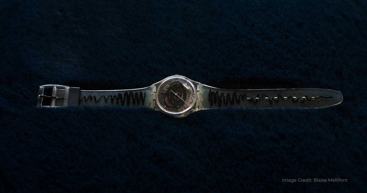 Gray vintage Swatch Watch laid out flat against a black background.
